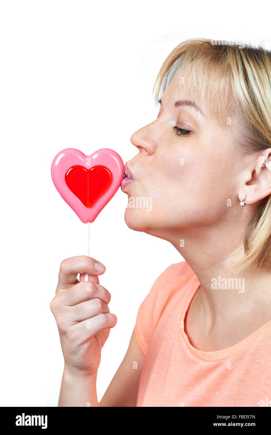 Felice ragazza baciare a forma di cuore ad lollipop su bianco isolato Foto Stock