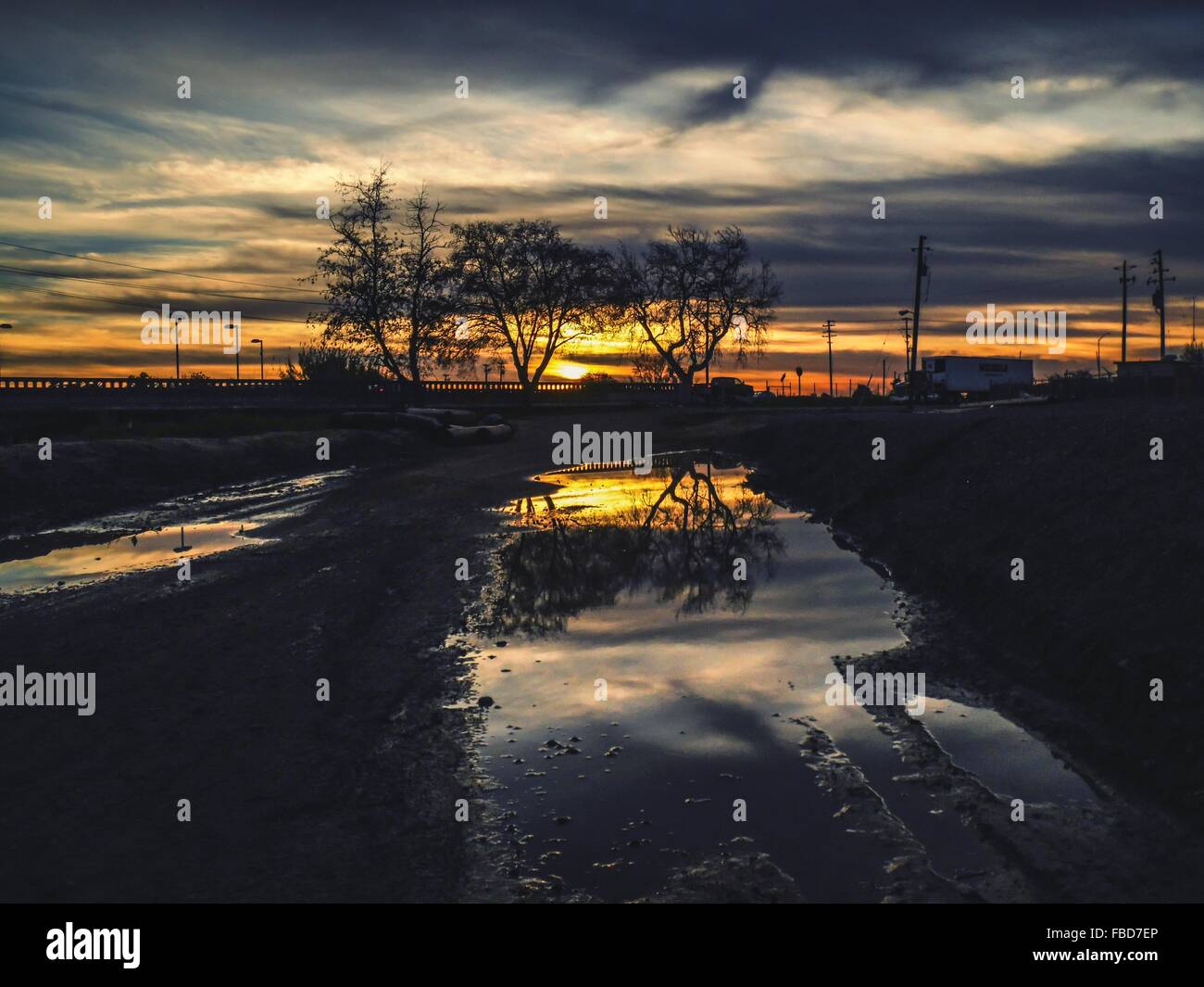 Cielo drammatico riflettendo nella pozza in primo piano Foto Stock