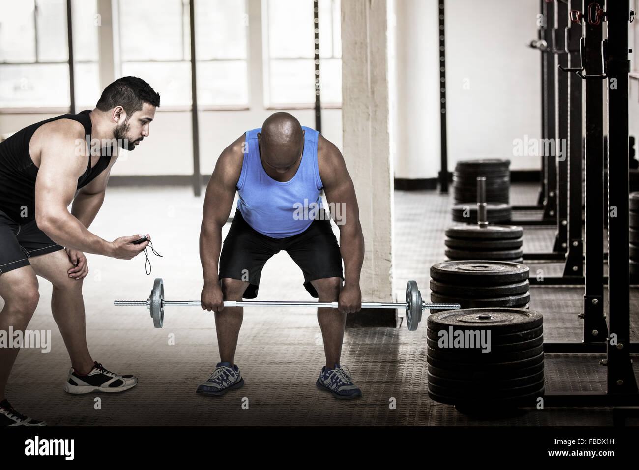 Immagine composita dell'uomo il sollevamento barbell con trainer Foto Stock