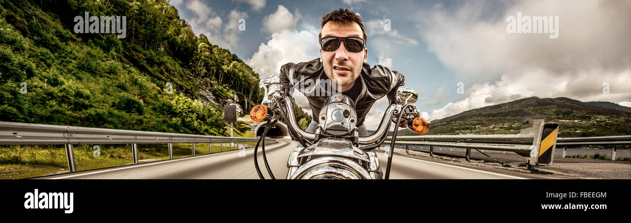 Funny Biker in occhiali da sole e giacca di pelle racing sulla serpentina di montagna. Filtro applicato in post-produzione. Foto Stock Funny Biker in occhiali da sole e giacca di pelle racing sulla serpentina di montagna. Filtro applicato in post-produzione. Foto Stock