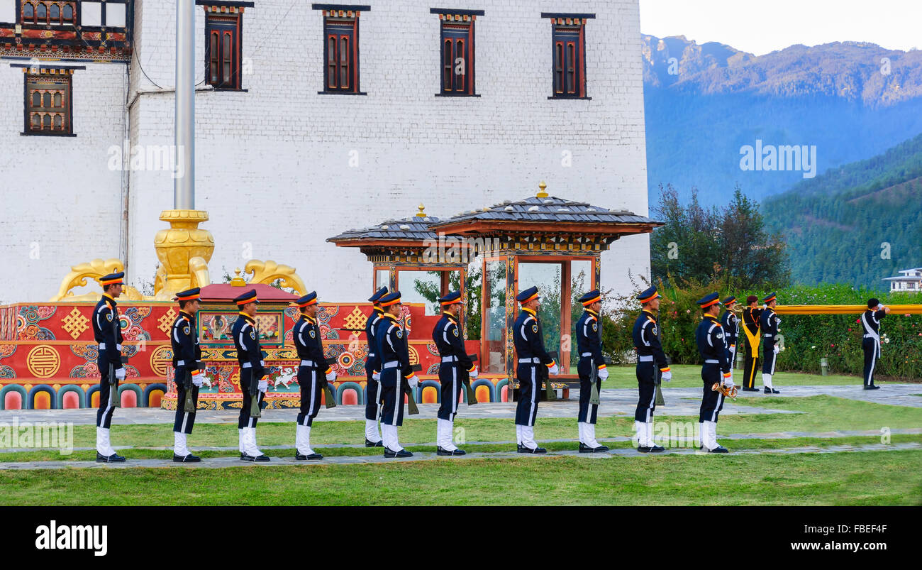 Il cerimoniale di abbassamento di bandiera al tramonto a Tashichho Dzong, sede del potere di governo bhutanese durante il crepuscolo, spazio di copia Foto Stock