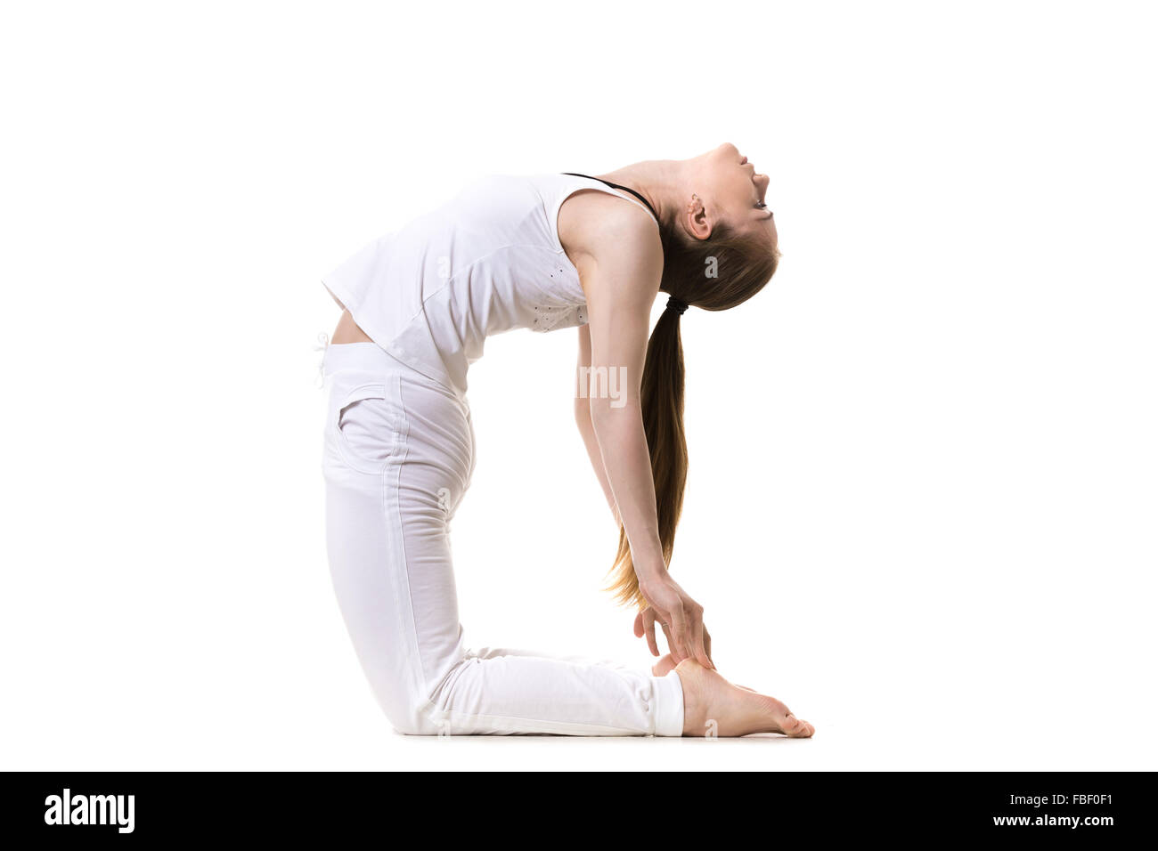 Giovani modello di fitness in bianco sportswear fare yoga o pilates formazione, asana Ustrasana (Camel Yoga posa), vista laterale, studio sho Foto Stock