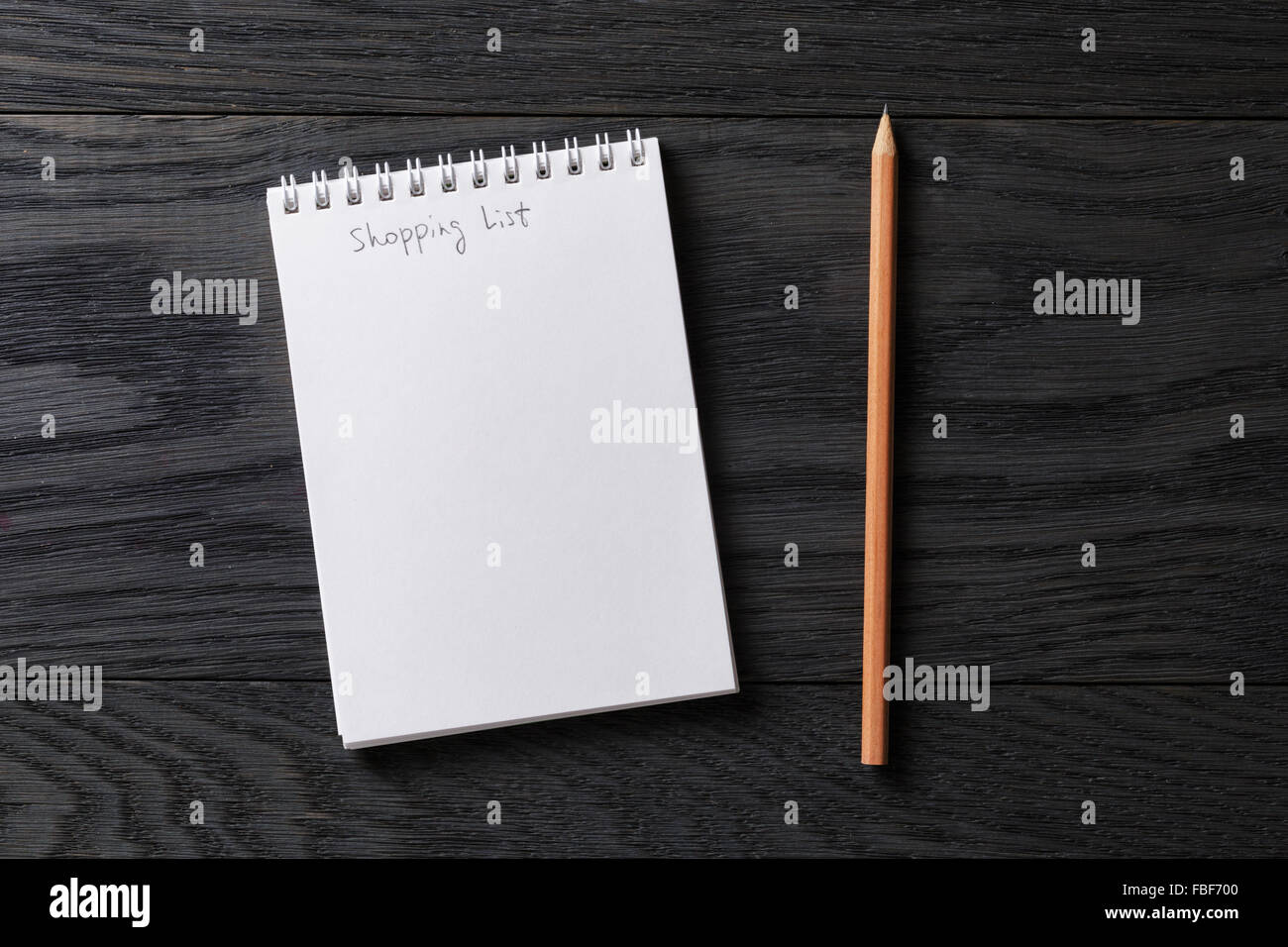 Shopping list la frase nel blocco note su grigio tavolo in legno Foto Stock