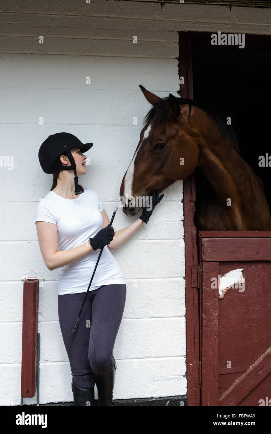 Pilota femmina con la frusta guardando a cavallo Foto Stock