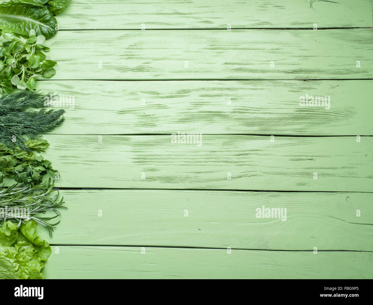 Erbe verdi sul verde sullo sfondo di legno. Foto Stock