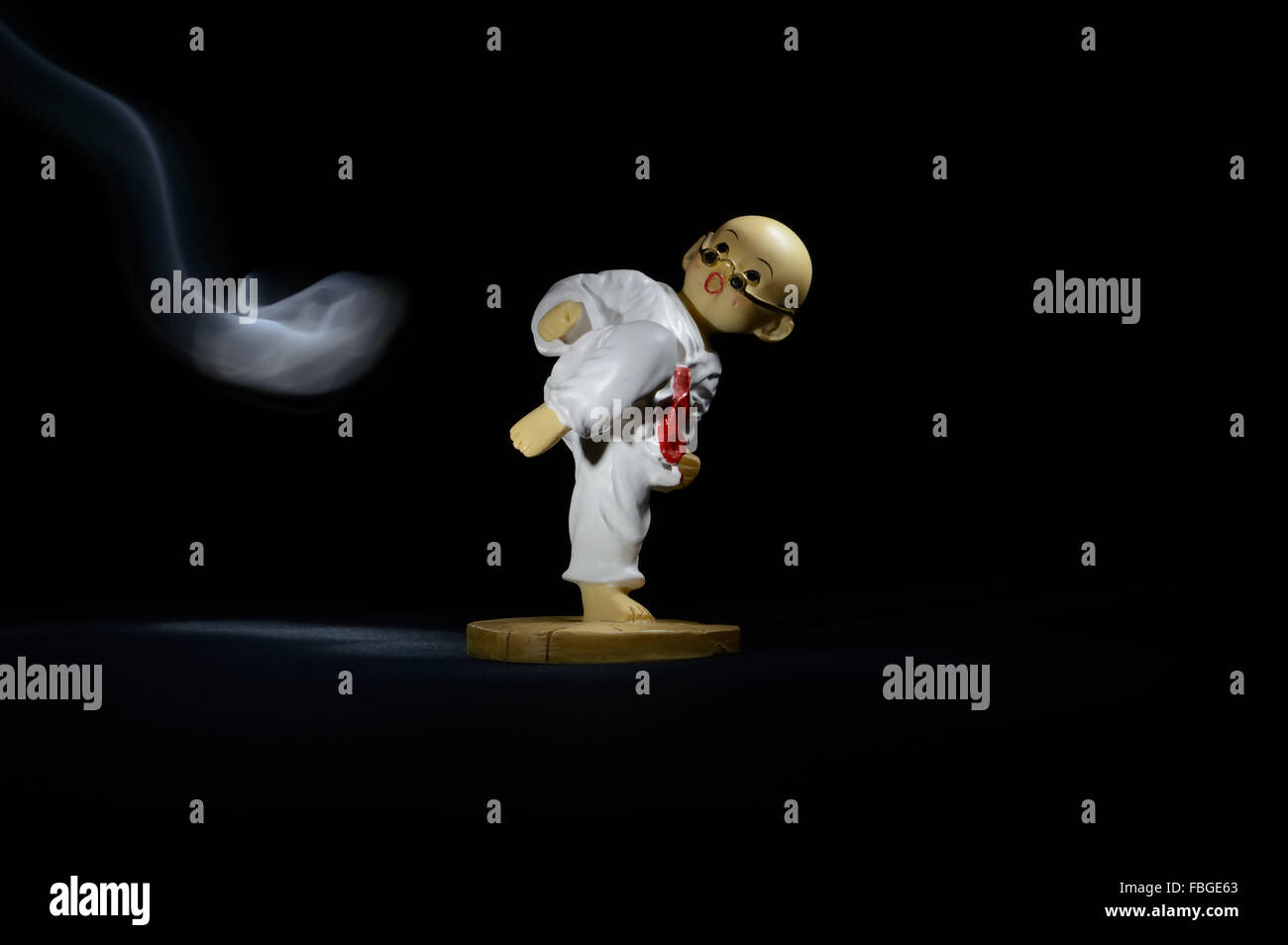 Modello Karate Fighter nella lotta contro la presa di posizione contro il fumo Jet su sfondo nero Foto Stock