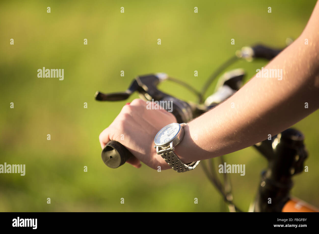 Bella giovane sportivo donna crampiformi mano maniglia di bicicletta in condizioni di luce solare intensa sul giorno di estate, close up Foto Stock