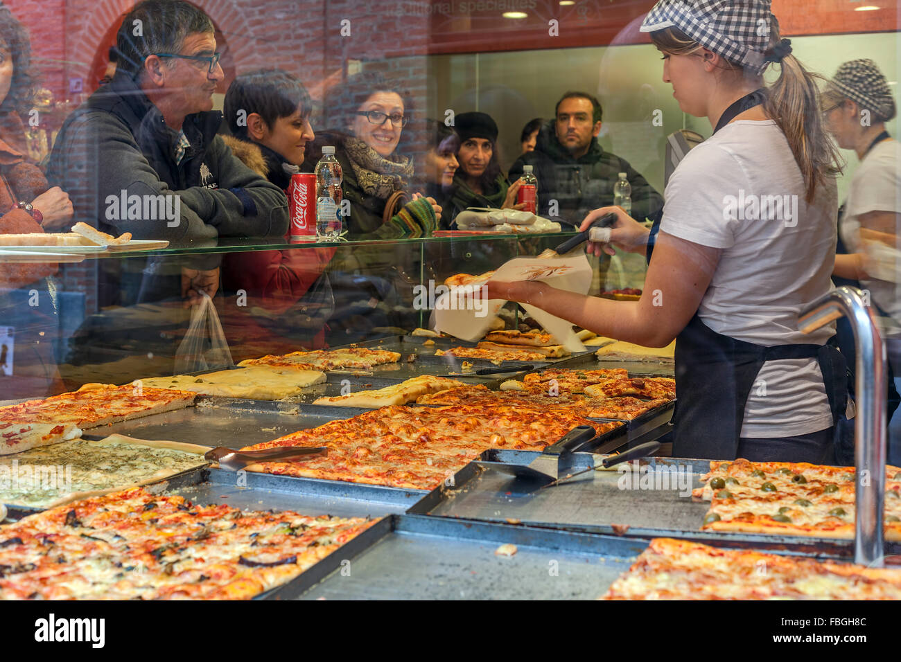 Le persone all'interno di tipiche pizzeria acquisto di pizza a Alba, Italia. Foto Stock