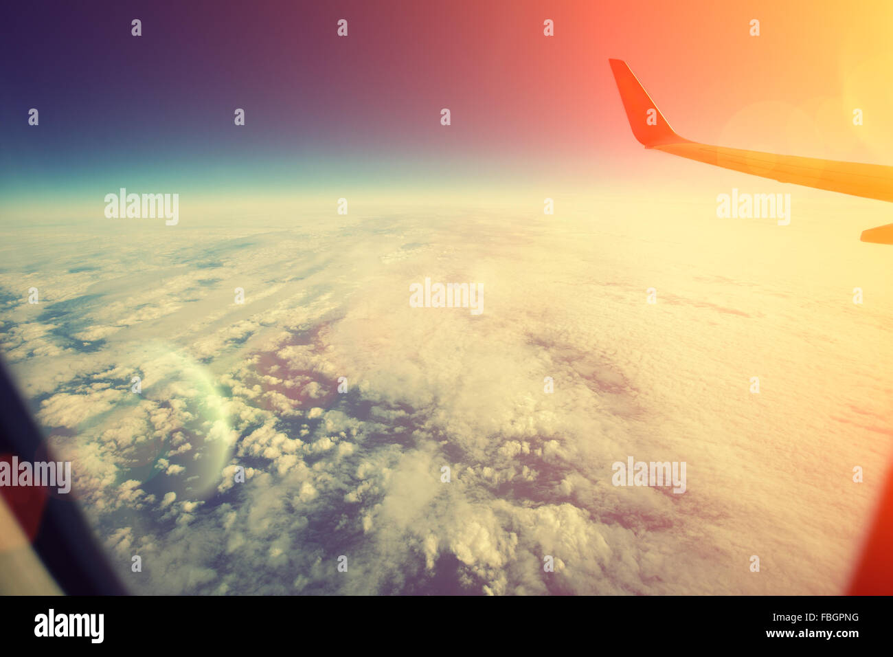 Aeroplano che vola sopra le nuvole rosa al tramonto Foto Stock