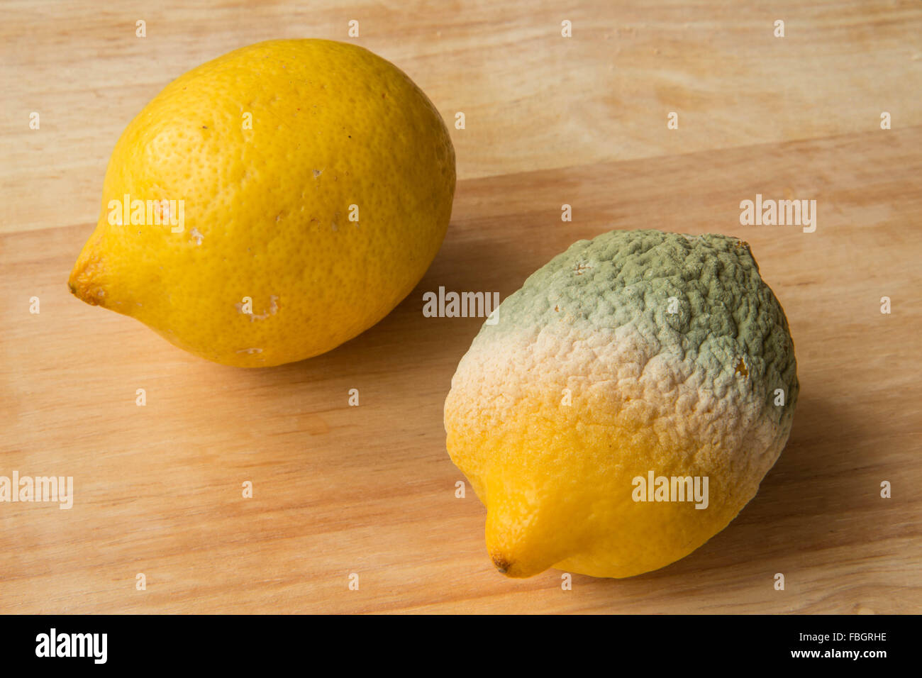 Limoni - una buona uno marcio - Sfondo legno Foto Stock