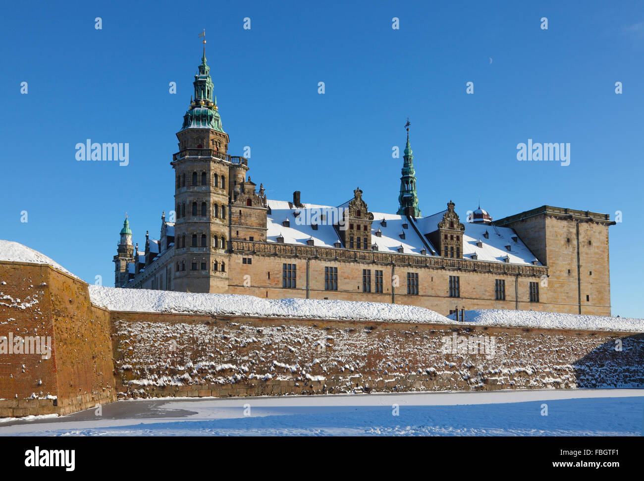 La coperta di neve il Castello di Kronborg a Elsinore, Helsingør, su una soleggiata giornata invernale e congelate, il fossato ed un cielo blu. Foto Stock