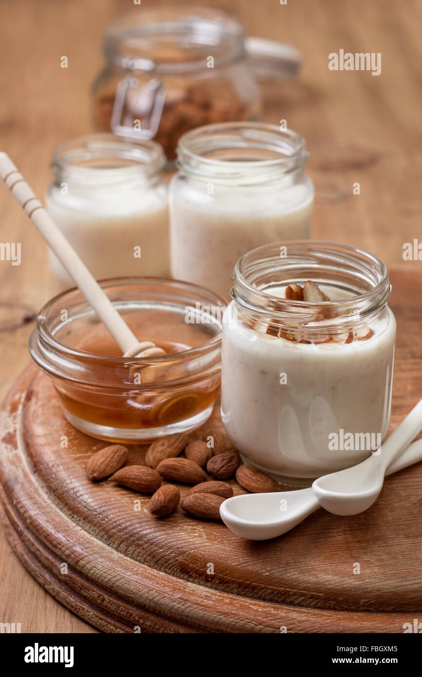 Yogurt fatto in casa latte di mandorla con farina di avena e miele su sfondo di legno Foto Stock