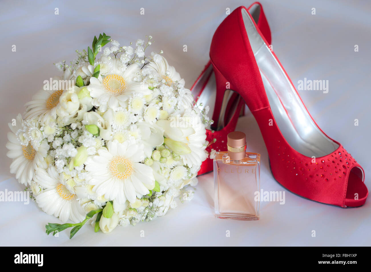 Sposa scarpe, bouquet e profumo su uno sfondo bianco. Foto Stock