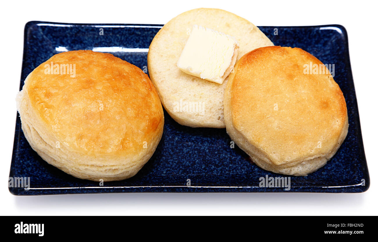 Golden Brown Fluffy latticello Buscuits colazione con burro sul piatto blu con sfondo bianco. Foto Stock
