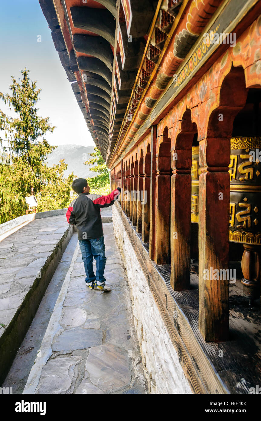 Giovane turista boy girando le ruote di preghiera di antico monastero a Thimphu Bhutan, Chang pista Kha Lakhang, landmark, spazio di copia Foto Stock