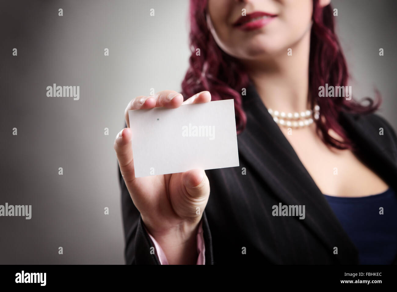 Close up studio shot di una donna d'affari tenendo una scheda vuota nel suo teso la mano destra Foto Stock