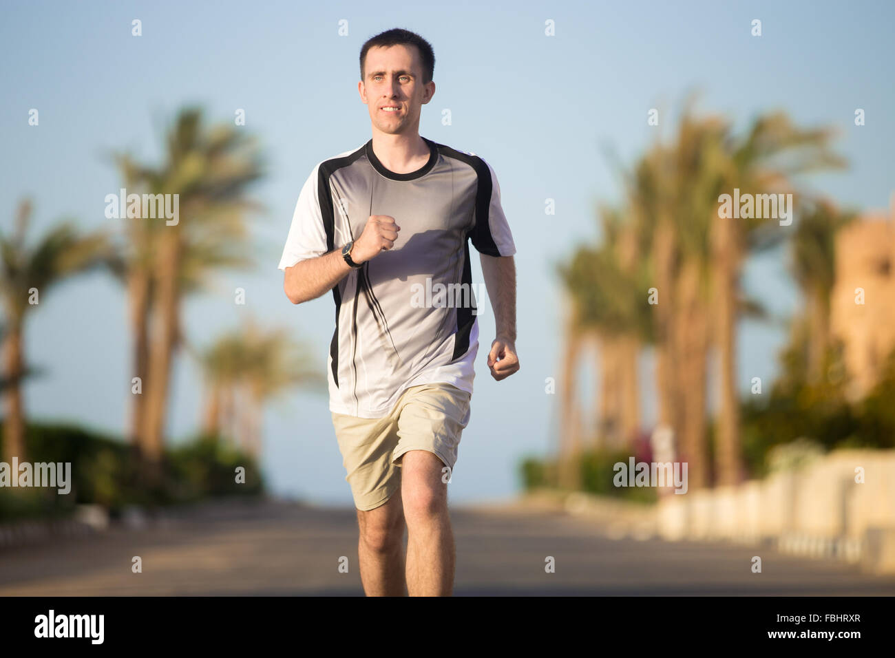 Uno stile di vita sano: sportivo positivo giovane uomo che lavora fuori all'aperto in estate sunny street nei tropichi, jogging sulla strada, pa Foto Stock