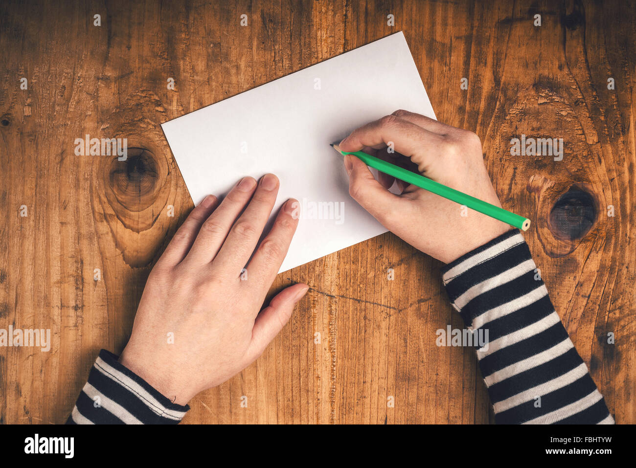 Donna scrivere l'indirizzo del destinatario sulla busta postale, mani femminili dal di sopra sulla scrivania in ufficio invio di lettera, vista dall'alto, toni rétro Foto Stock