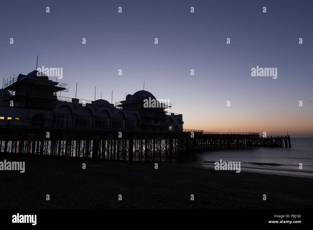 Sunrise dietro South Parade pier a Southsea. Fredda mattina fresco risultante in un bagliore di formatura e riflettendo in mare. Foto Stock