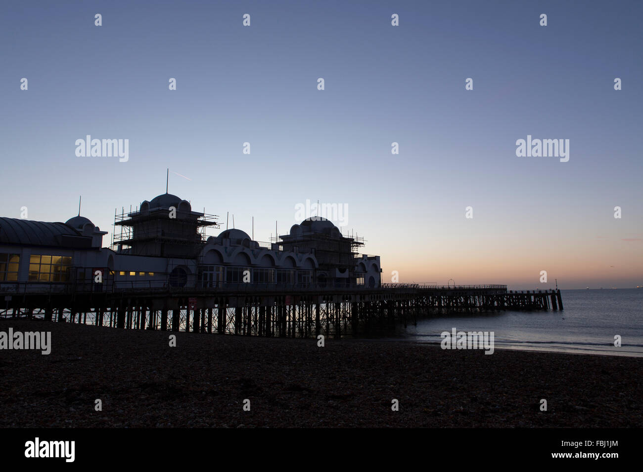 Sunrise dietro South Parade pier a Southsea. Fredda mattina fresco risultante in un bagliore di formatura e riflettendo in mare. Foto Stock