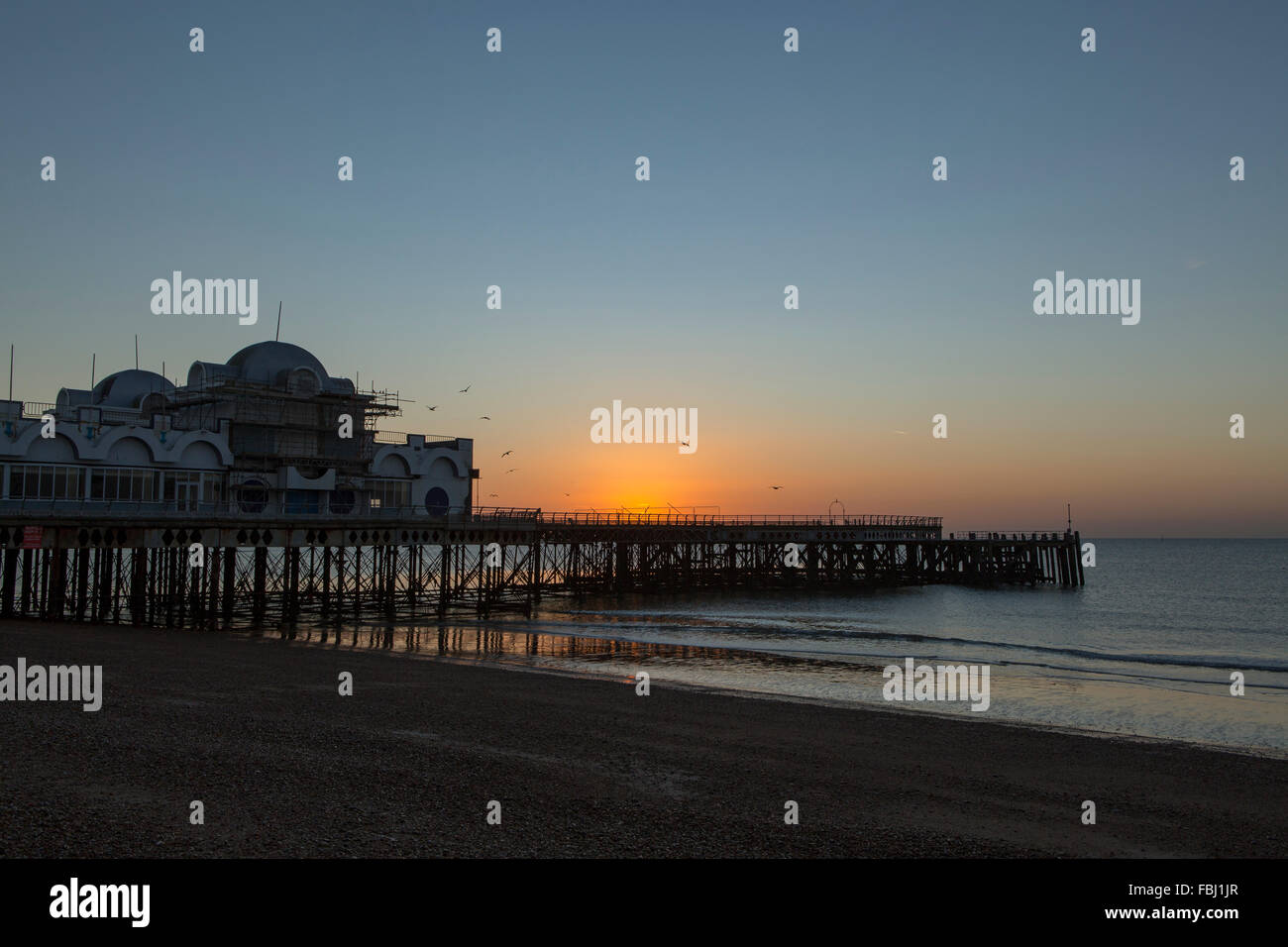 Sunrise dietro South Parade pier a Southsea. Fredda mattina fresco risultante in un esplosione di colori che riflettono in mare. Foto Stock