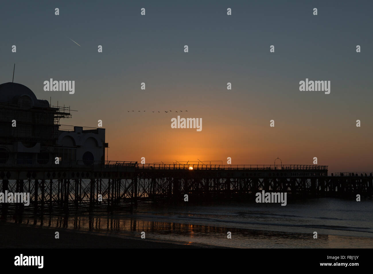 Sunrise dietro South Parade pier a Southsea. Fredda mattina fresco risultante in un esplosione di colori che riflettono in mare. Foto Stock