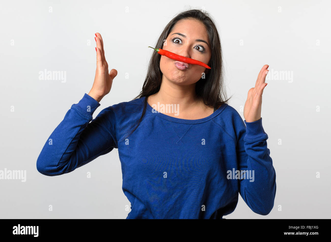 Pippo una donna con il red hot chili pepper i baffi equilibrato sul suo labbro strizzare gli occhi e gesti con le mani, la parte superiore del corpo sul whi Foto Stock