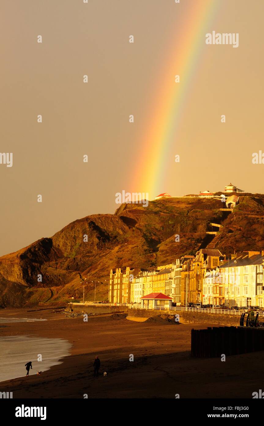 La gente che camminava sul Aberystwyth Beach in tarda serata la luce del sole e rainbow Ceredigion nel Galles Cymru K GB Foto Stock