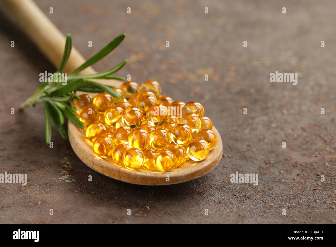 Integratore alimentare di olio di pesce capsule in un cucchiaio di legno - cibo sano Foto Stock
