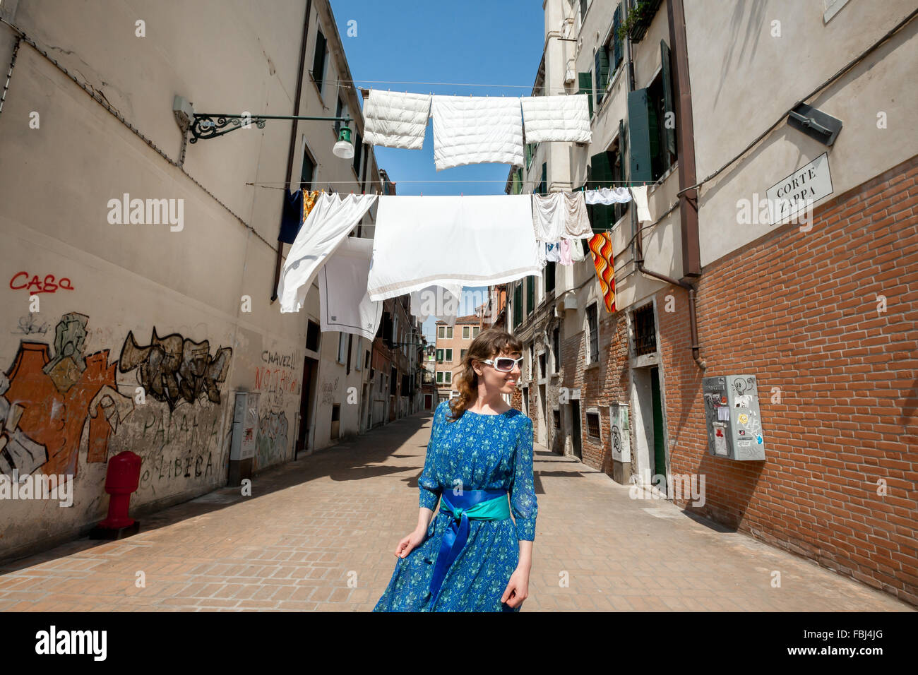 Sorridenti ragazza fuori sulla passeggiata a Venezia, sullo sfondo bianco di asciugatura biancheria tra le case strette backstreet Foto Stock