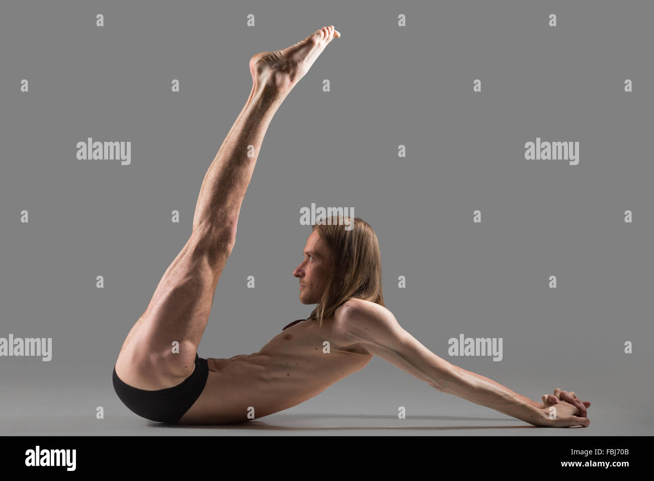 Sporty muscolare yogi giovane uomo a fare gli esercizi per gli addominali e spalle, il sollevamento delle gambe, studio shot on dark Foto Stock