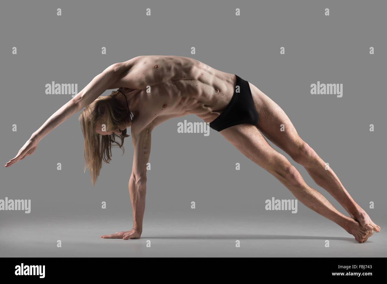 Sporty muscolare yogi giovane uomo che fa la variazione della posizione del cobra pongono, Vasisthasana postura, esercizio per addome e della colonna vertebrale, studio Foto Stock