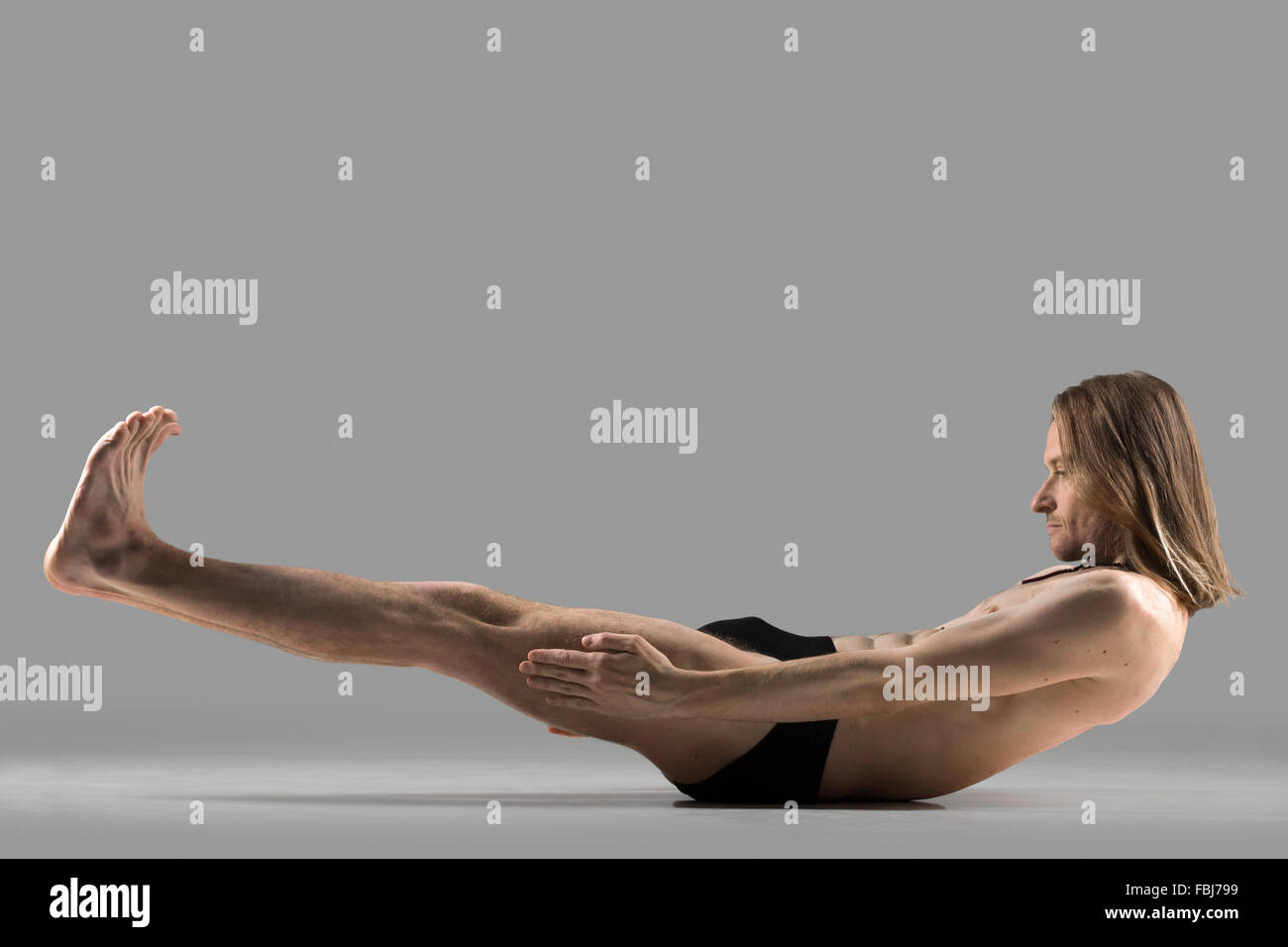 Giovane sportivo yogi uomo fare yoga posa per muscoli addominali forza, asana Ardha Navasana, bassa barca posture yoga, studio shot o Foto Stock