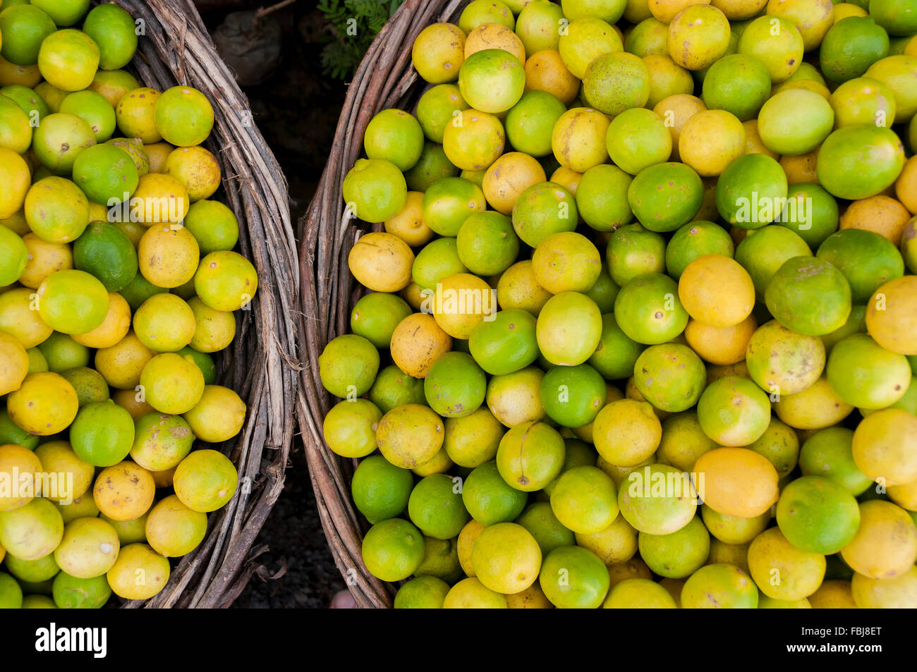 Limes un limoni in due ceste al mercato asiatico Foto Stock