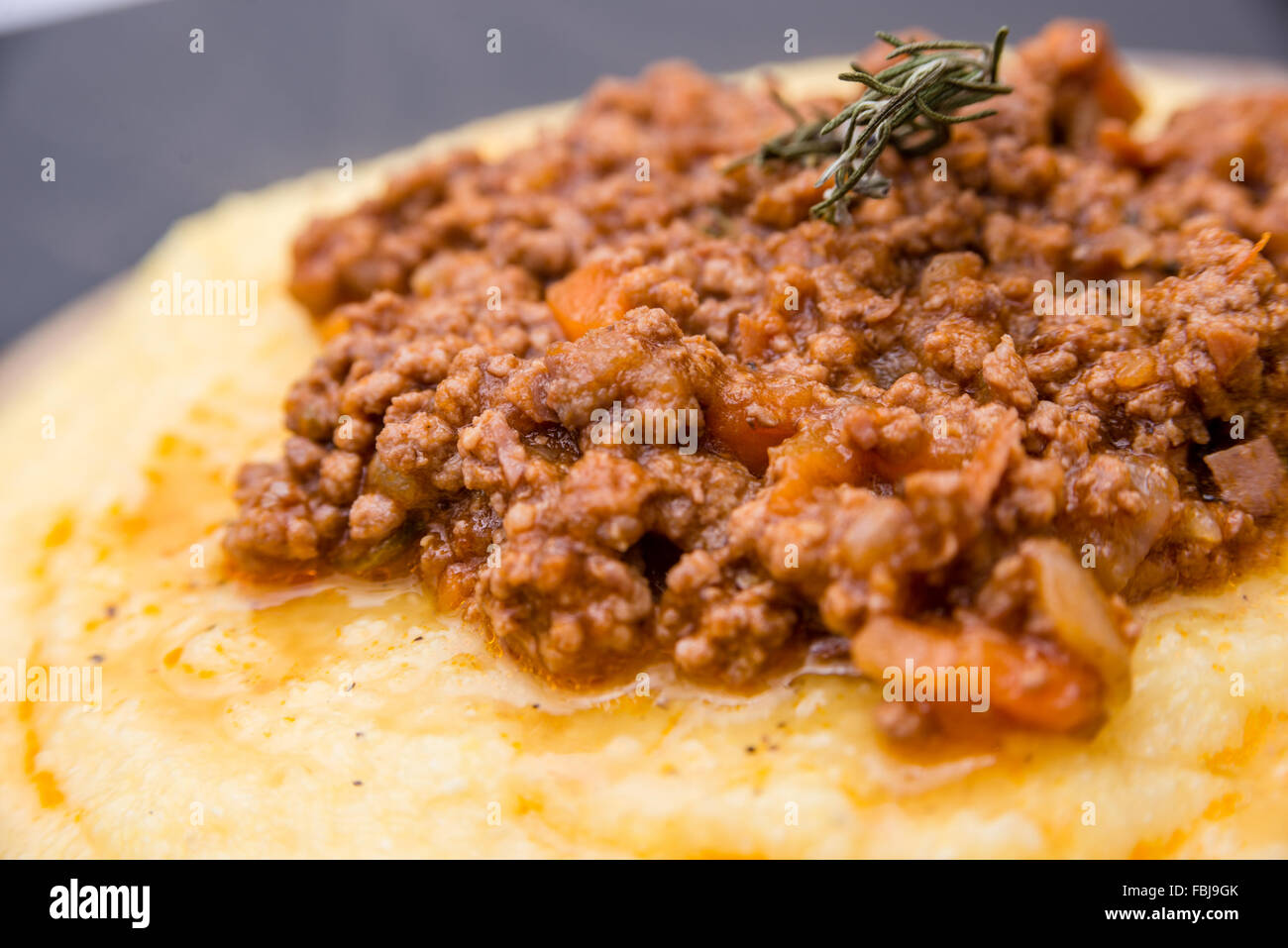 Una vista ravvicinata di un tradizionale piatto italiano: polenta con zuppa di bolognese (ragu) Foto Stock