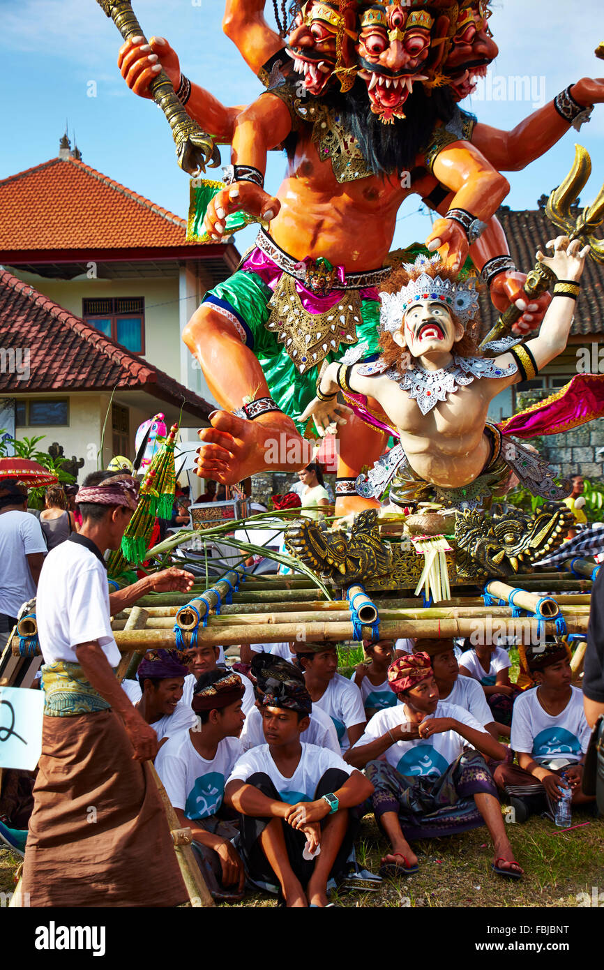 Bambini seduti sotto la statua, ornati di costumi abbigliamento festivo, nuovo anno celebrazione, tradizionale cerimonia, Nyepi, Bali, Indonesia, Asia Foto Stock