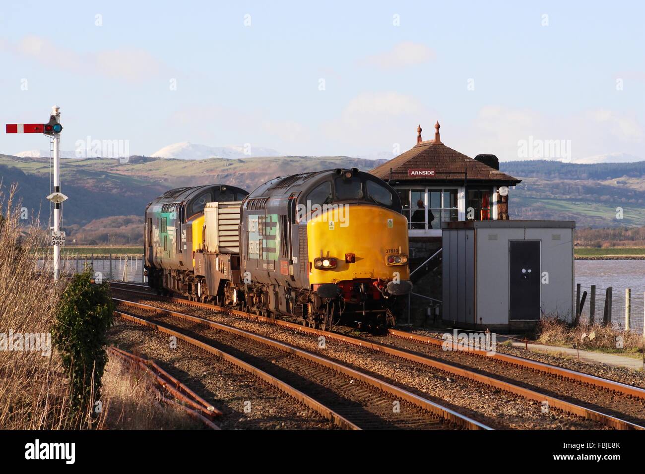 DRS liveried classe 37 locomotive diesel con un pallone nucleare treno da Arnside casella segnale sul Furness linea ferroviaria in Cumbria Foto Stock