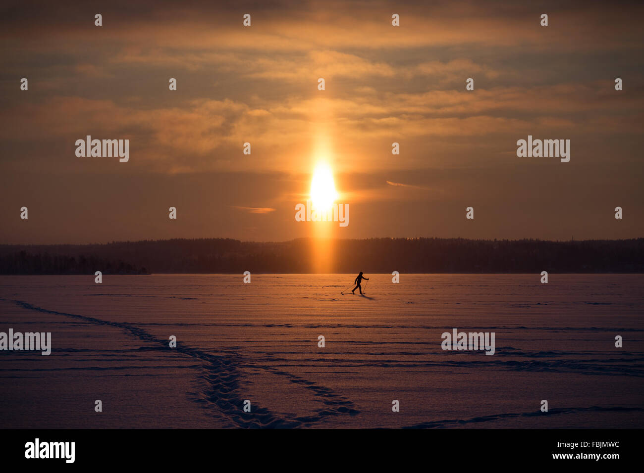 Silhouette di un fondista sci presso un lago ghiacciato in Finlandia in una giornata di sole. Foto Stock