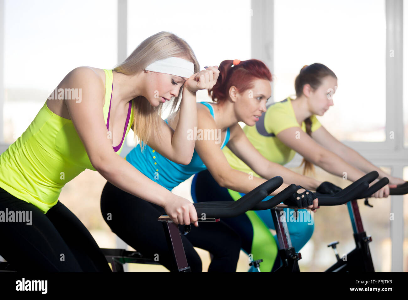 La pratica di fitness, gruppo di montare tre femmine bellissime escursioni in bicicletta in sports club, facendo esercizi cardio per dimagrire in classe Foto Stock