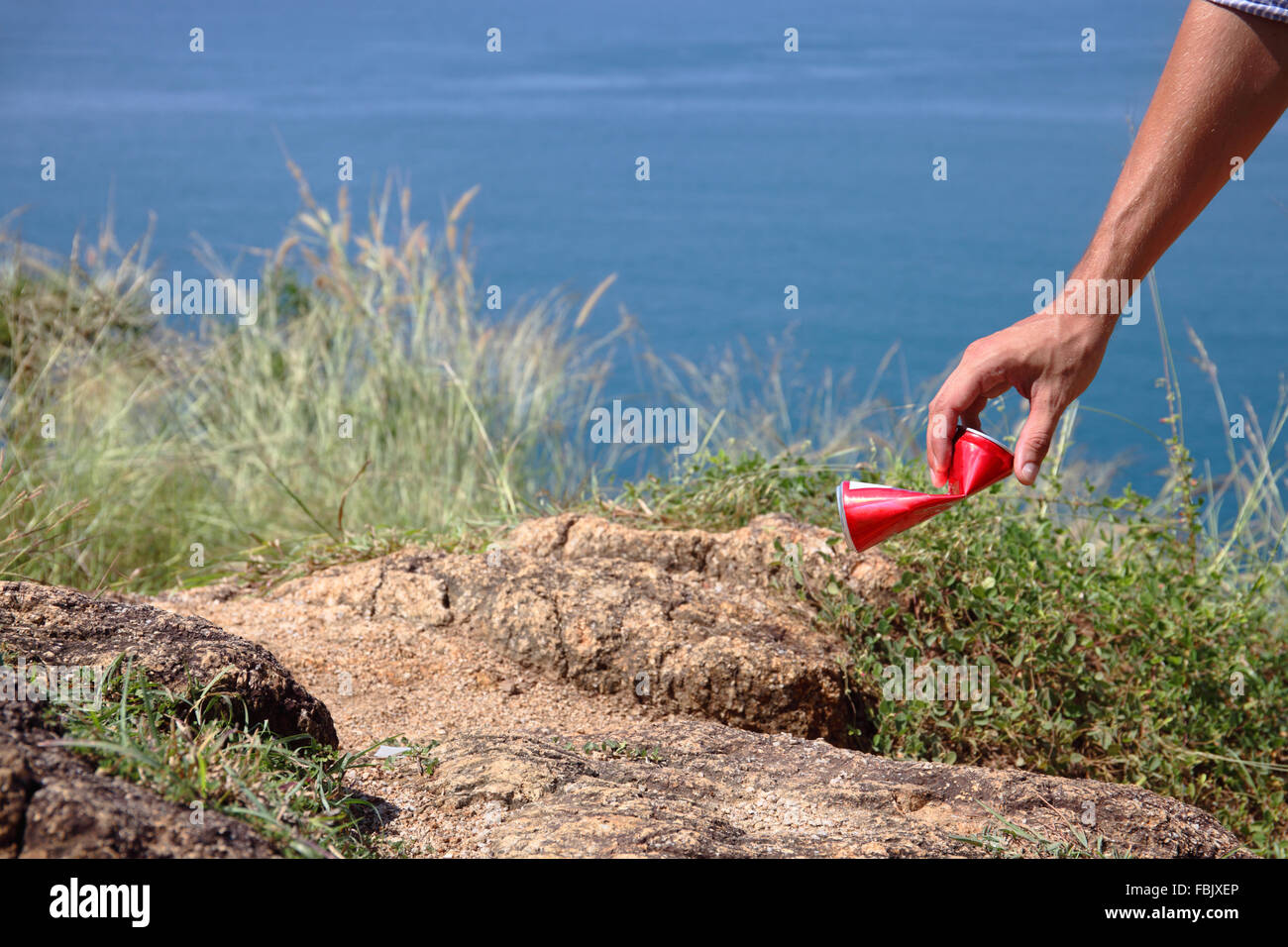 Man picking up figliata possono su roccia in riva al mare a Foto Stock