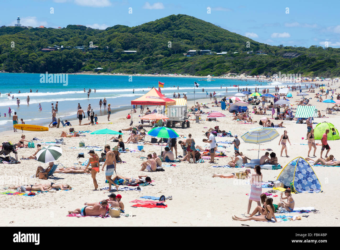 Occupato spiaggia principale in Byron Bay su New South Wales costa nord, con il faro in distanza,l'Australia Foto Stock