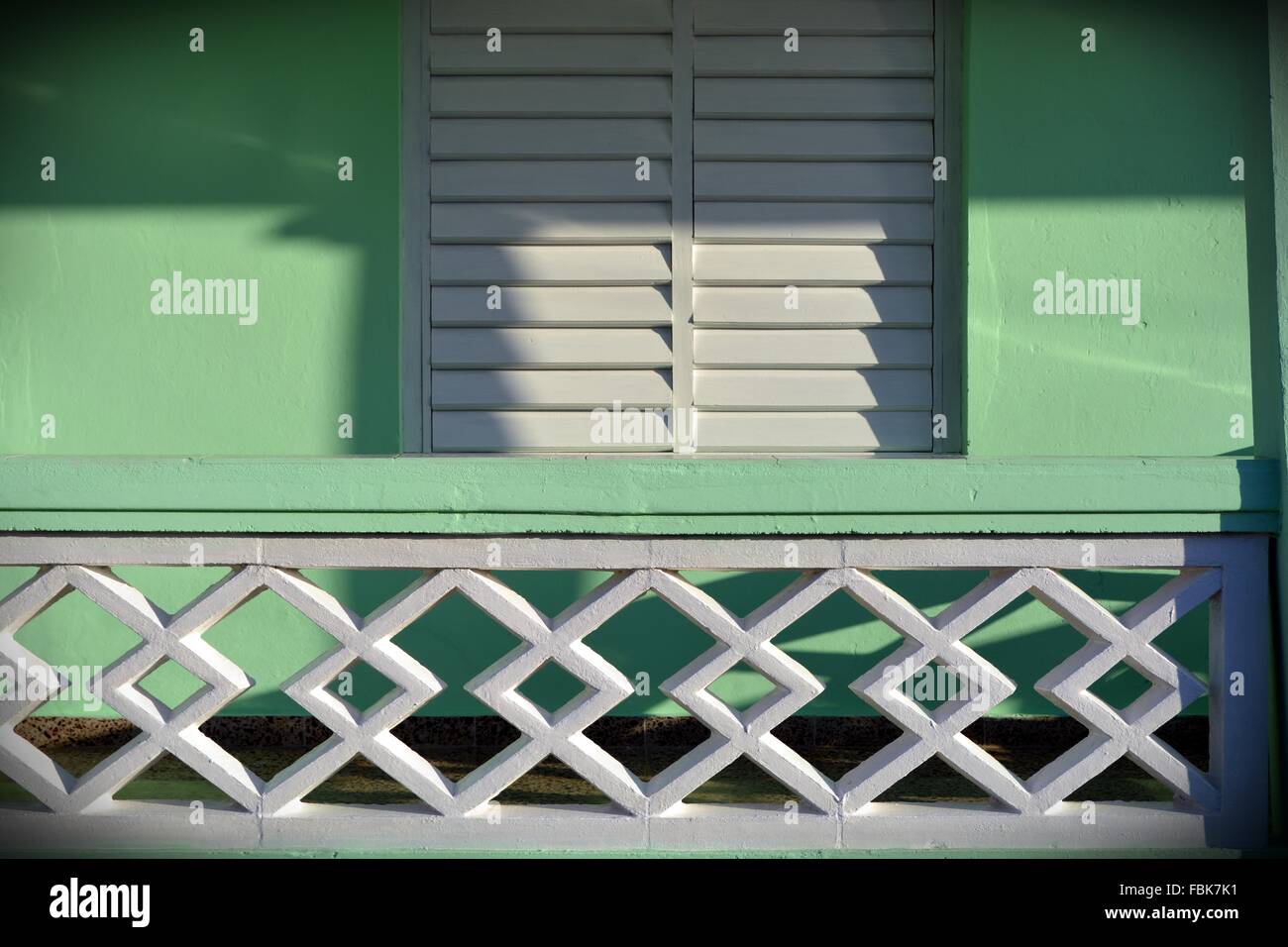 Dettaglio di stile coloniale bungalow veranda in Vinales con il sole sul dipinto di bianco di persiane di legno e colori pastello pareti verde Foto Stock