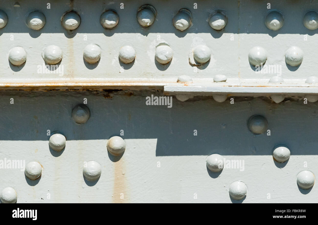 Close-up di rivetti in acciaio verniciato con superficie alcune macchie di ruggine, parzialmente le ombre di colata dall'alto. Foto Stock