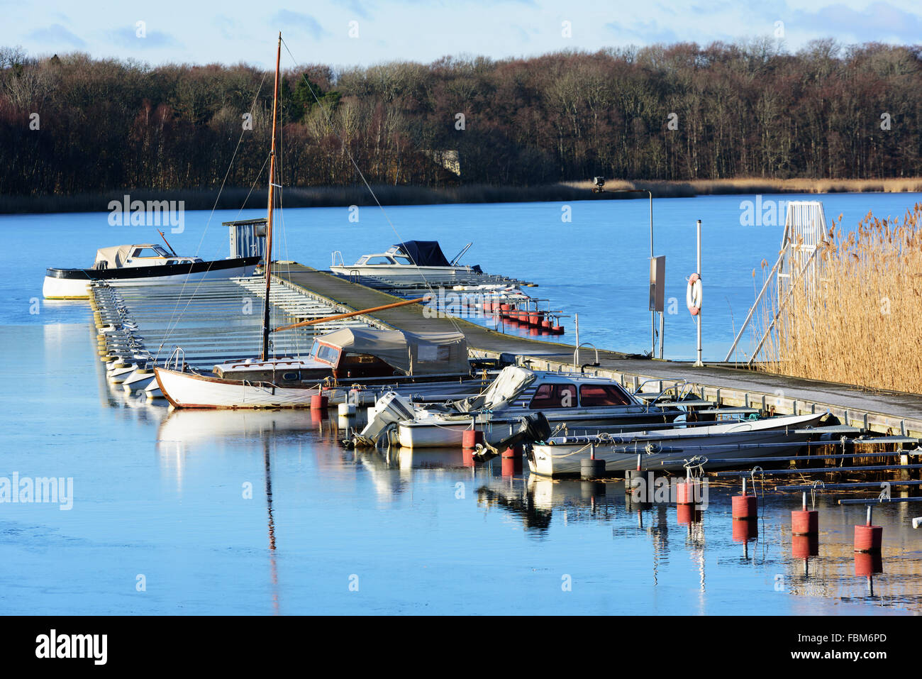 Un marina con pochissime barche in inverno. Il ghiaccio sottile si sta lentamente prendendo una presa sulle barche che vengono lasciati in mare. Il surround Foto Stock