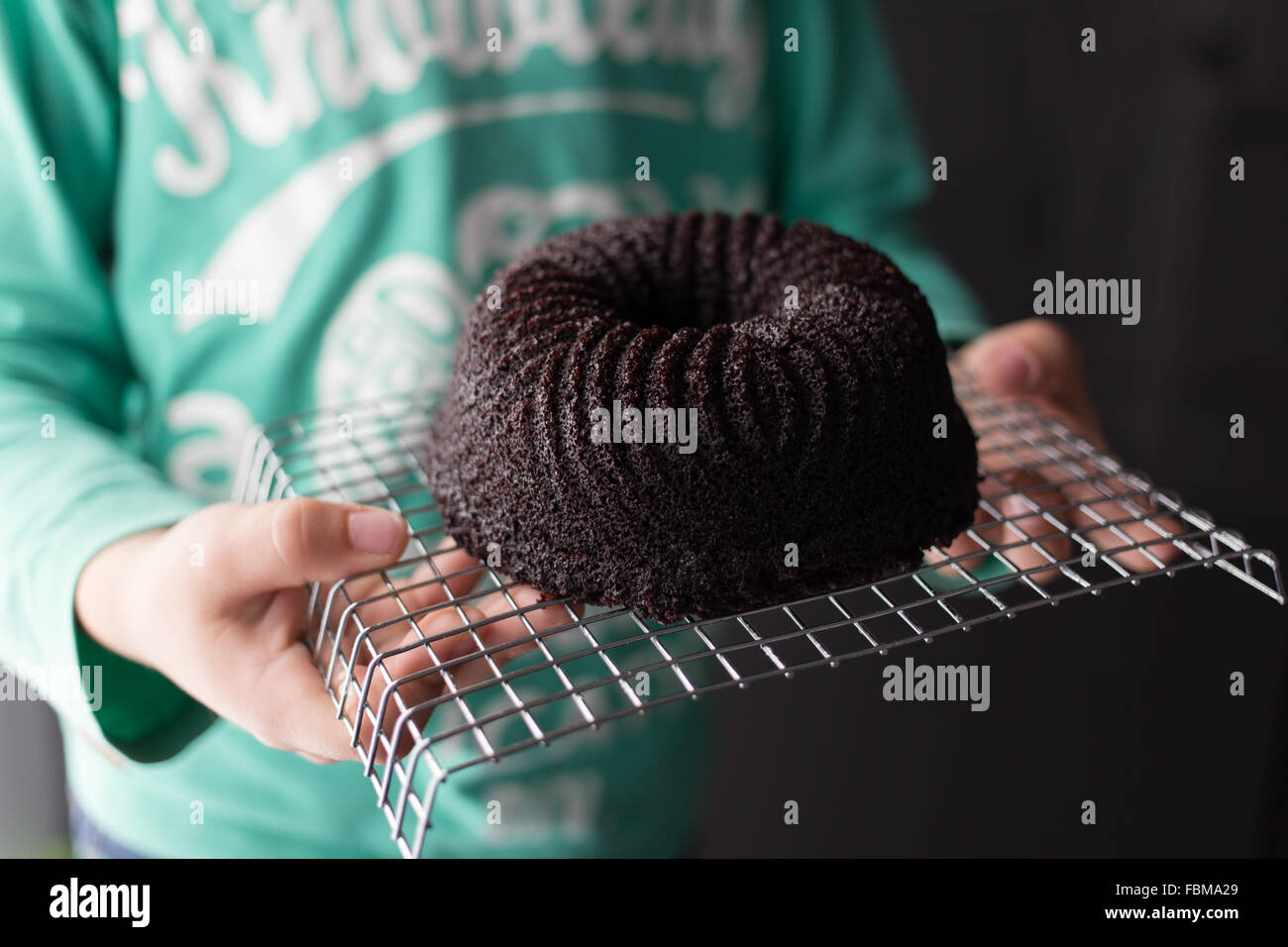 Ragazzo tenendo un cioccolato pan di spagna sul filo di un raffreddamento per rack Foto Stock