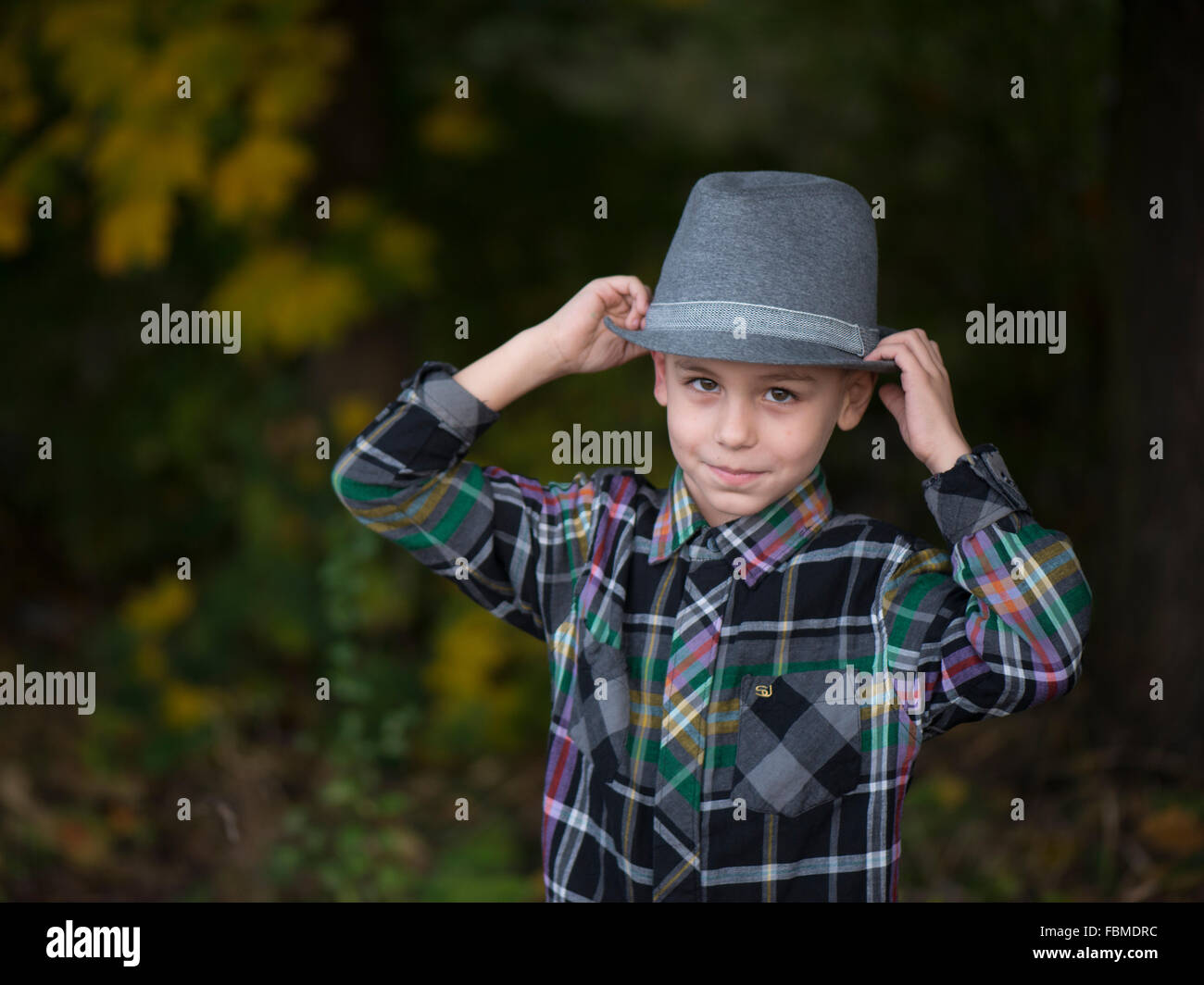 Ragazzo sorridente mettendo su un cappello Foto Stock