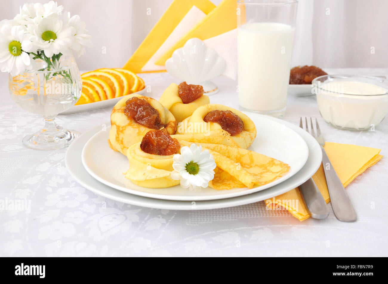 La prima colazione con pancake, confettura di albicocca e latte e arance Foto Stock