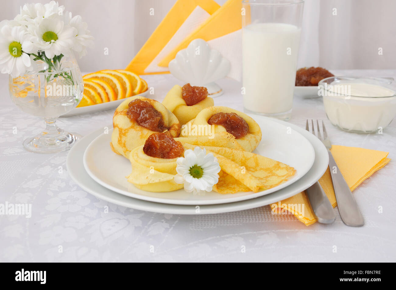 La prima colazione con pancake, confettura di albicocca e latte e arance Foto Stock