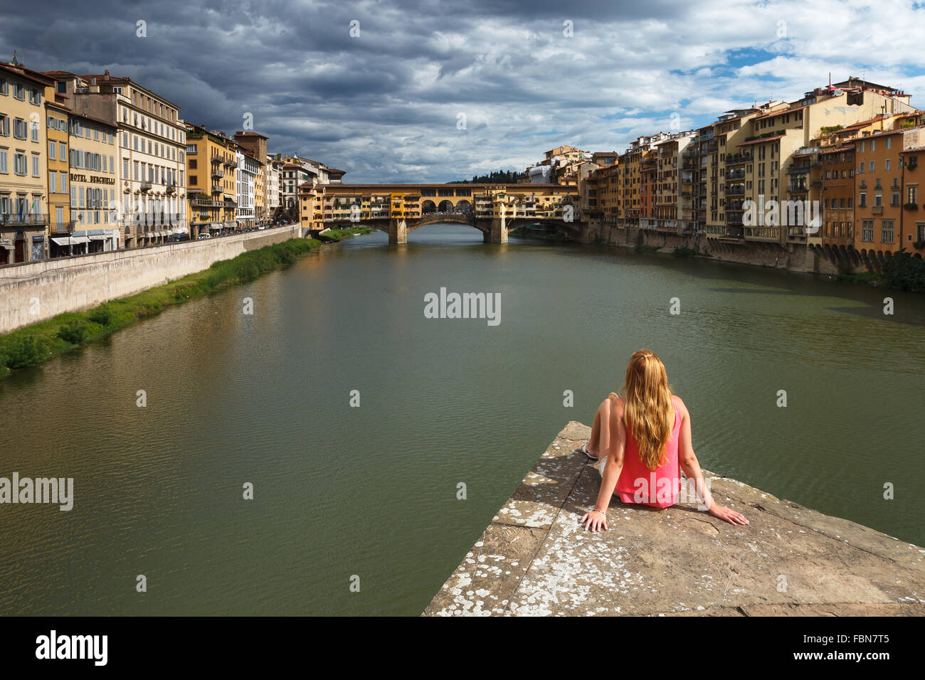 Una giovane donna godendo la vista del Ponte Vecchio e sul fiume Arno, Firenze, Toscana, Italia. Foto Stock