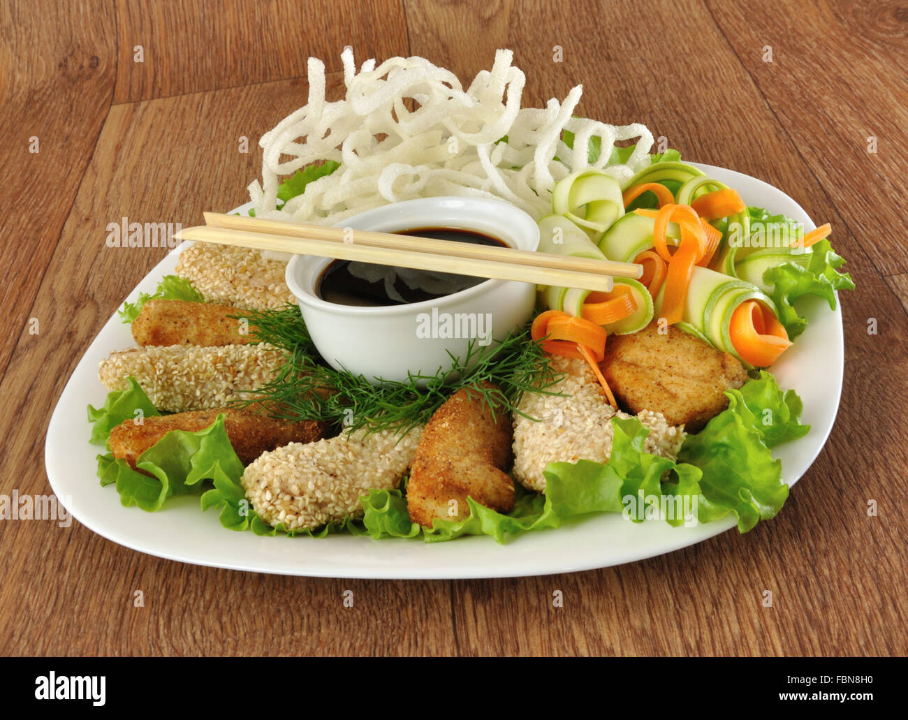 Filetto di pollo nel pangrattato e sesamo con riso fritto Tagliatelle con verdure Foto Stock